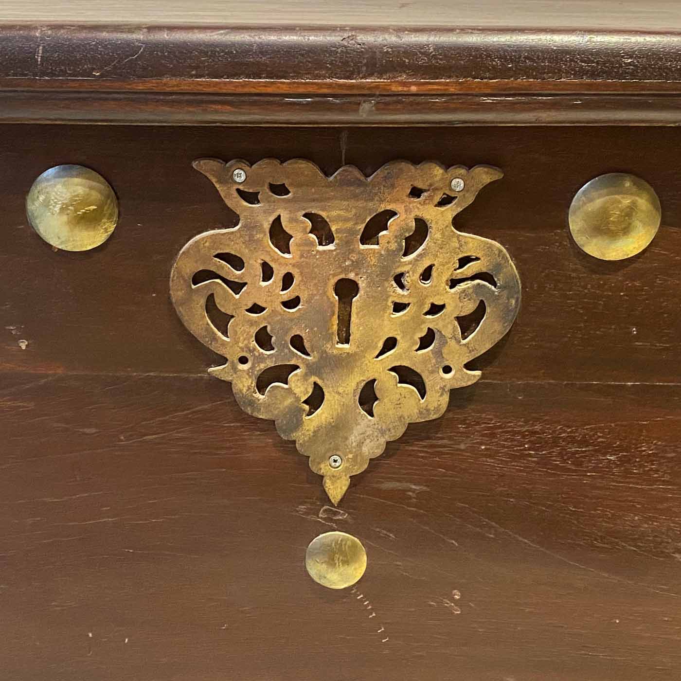 An antique Indian trunk hand-carved from teakwood and adorned with brass details.