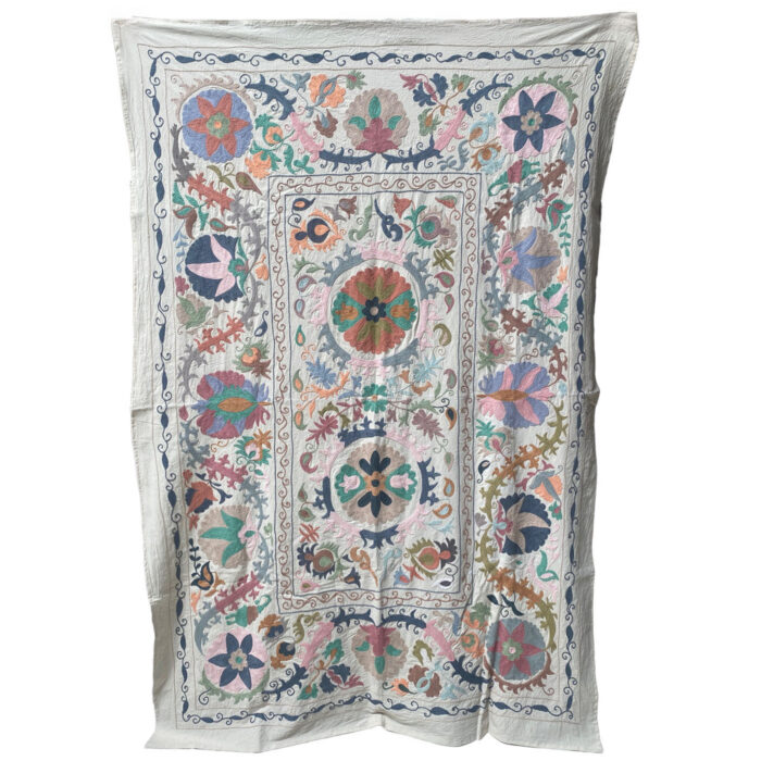 A heavily embroidered suzani textile with pastel colors.