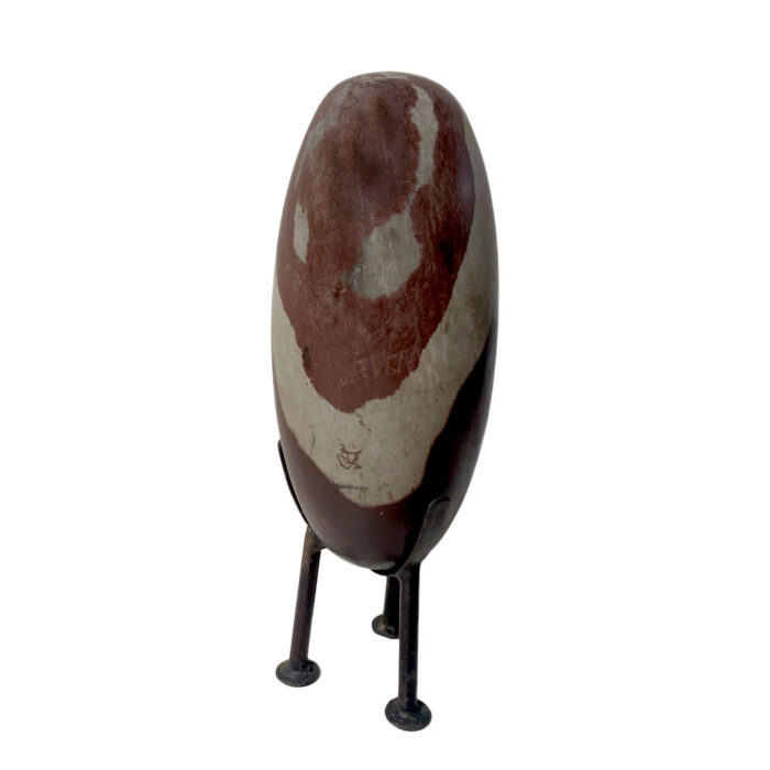 Hand-carved solid stone egg-shaped sculpture on iron stand.